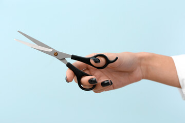 Female hairdresser with scissors on blue background, closeup