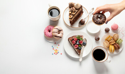 Table with various cookies, donuts, cakes,  coffee cups on white  background.