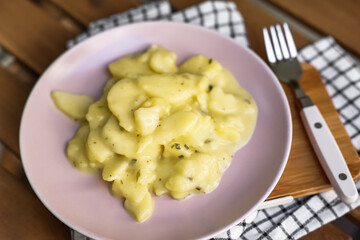 Plate with creamy potato salad and fork on wooden table
