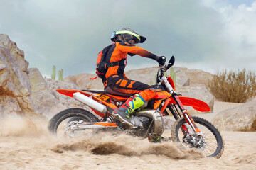 Obraz premium Young man practice riding dirt motorcycle. Splashing sand