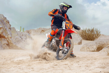 Young man practice riding dirt motorcycle. Splashing sand