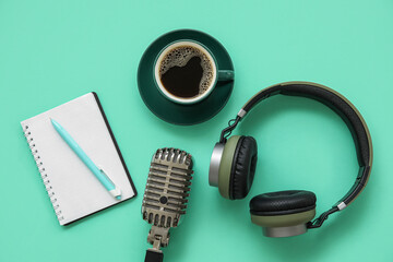 Notebook with microphone, headphones and coffee cup on green background