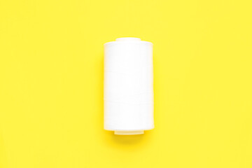 White thread spool on yellow background