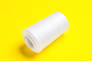 White thread spool on yellow background