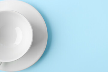White cup with saucer on blue background, closeup