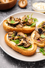 Plate of tasty toasts with cream cheese and mushrooms on grunge background, closeup