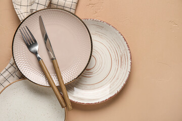 Empty plates with cutlery and napkin on beige background
