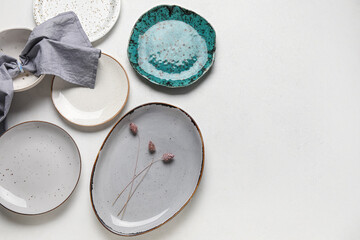 Different plates with floral decor and napkin on grey background