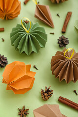 Paper Christmas balls with cinnamon, fir cones and anise on green background