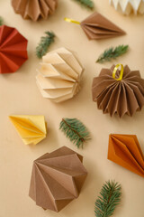 Paper Christmas balls with fir branches on beige background, closeup