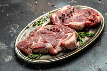 meat with seasoning. Pieces of raw pork steaks with rosemary and pepper on a dark background. banner, menu, recipe place for text, top view