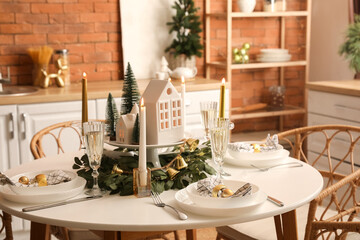 Christmas table setting with candle holders and fir trees in kitchen