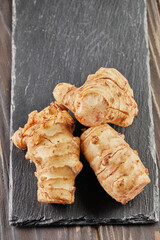 Fresh ginger on black stone on wooden background