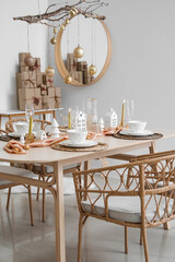 Interior of light room with dining table, tree branches and Christmas balls