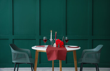 Table setting with candle holders and Christmas trees near green wall
