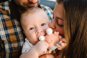 Happy family, parenthood and people concept - mother, father with baby at home. Portrait of young smiling family with son on the hands.