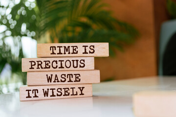 Wooden blocks with words 'Time is precious waste it wisely'.