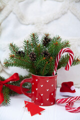 Christmas cup with pattern, Christmas tree branches and decorations nearby. White background