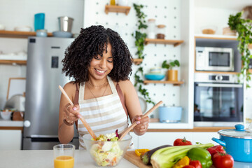 Young woman preparing vegetable salad in her kitchen. Healthy lifestyle concept beautiful woman...