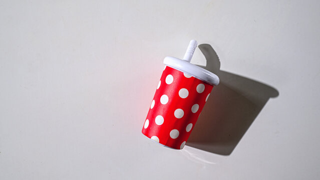 Red with white polka dots, a cocktail glass, with a straw for children.