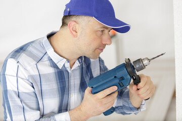 mid-adult man drilling hole in wall