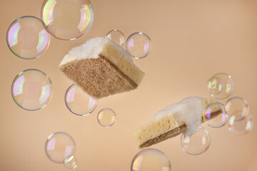 Natural dishwashing sponge with soap bubbles over beige background. Eco friendly housework objects.