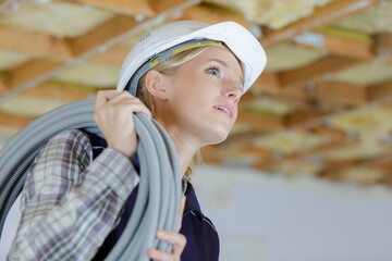 female builder carrying cable on her shoulder