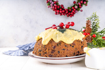 Traditional Christmas english pudding dessert. Homemade fruit pudding, with custard creme anglaise. Sweet aromatic fruit cake for Christmas, New Year dinner on cozy decorated background