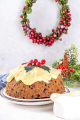 Traditional Christmas english pudding dessert. Homemade fruit pudding, with custard creme anglaise. Sweet aromatic fruit cake for Christmas, New Year dinner on cozy decorated background