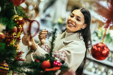Young woman selecting christmas decorations in decorative goods shop. The girl buys Christmas decorations.