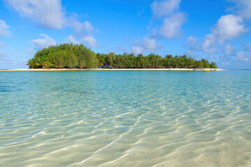 A small tropical island in the rippling waters of a shallow lagoon (Koromiri Island in Muri Lagoon, Rarotonga, Cook Islands)