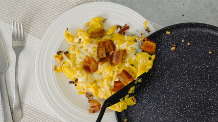 Serving breakfast. Scrambled eggs fried with cheese and bacon.