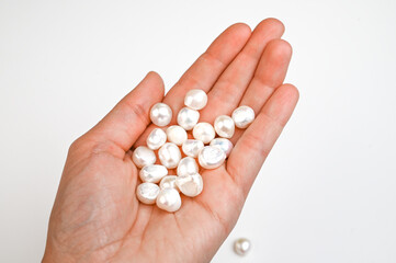 Close-Up of woman hand with pearl bead in female hand. Hand with string of baroque pearls