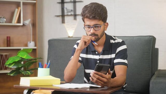 Young man using mobile phone for writing notes at home - concept of technology, learning and intelligence.