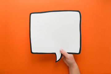 Speech bubble in hand on an orange background. Comic cloud with a place for text