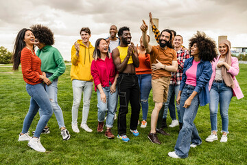 Fototapeta premium Cheerful group of happy multiracial friends having fun together outdoors in the city park. People enjoying a vacation. Friendship and diversity concept.