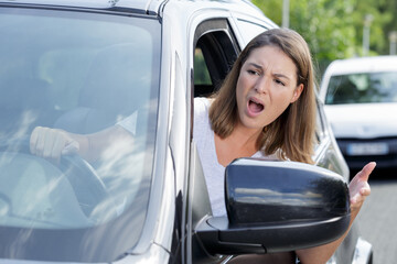 unhappy girl is actively gesticulating behind the wheel