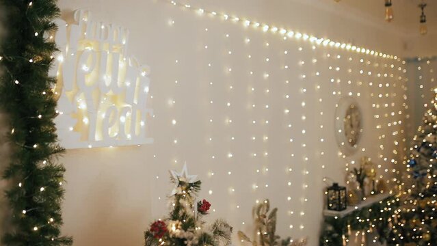 Wall decorated for Merry Christmas and Happy New Year celebration. Shiny sparkling garland lights bokeh on unfocused background with fir tree and branches