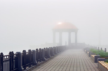 Architectural landscape of the rotunda on the embankment in the fog. Sun glare on the transparent...