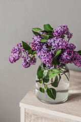 A bouquet of fresh lilacs in a glass vase top view.