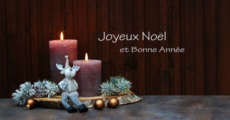 Carte de Noël : Bougies allumées avec décorations de Noël devant un mur en bois.  Joyeux Noël...