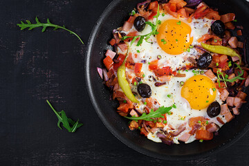 Fried eggs with vegetables on pan - pepperoni, tomatoes, ham, onion and black olives. Ketogenic...