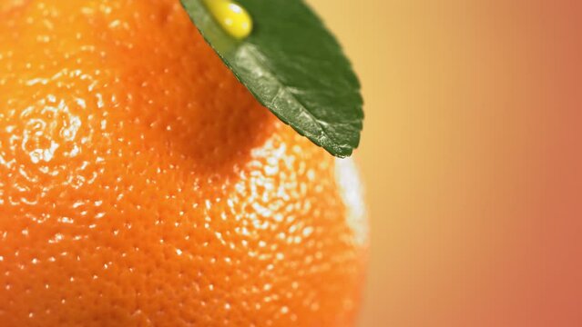 Drop falling from leaf of orange on nature background. Spa Skincare cosmetics and beauty concept