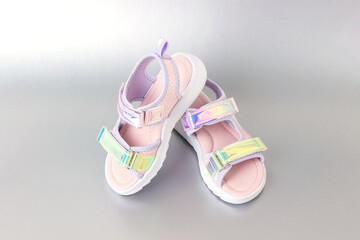 Stylish holographic sandals for kids on grey background. Shiny fashion summer shoes