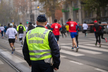 Belgrade, Serbia 27.11.2022 Police officer overwatching Runners that compete in race on Traditional Belgrade Marathon and Half Marathon on cold November day during Fog and high Air Pollution. 