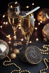 Black caviar in a mother-of-pearl spoon and jar and glass of champagne with Christmas decoration