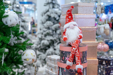 Christmas long-legged gnome in a suit with a scandinavian ornament on the background of boxes with...