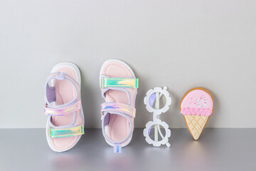 Stylish holographic sandals for kids on grey background. Shiny fashion summer shoes