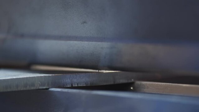 Hydraulic sheet bender slowly bends metal blank laid by the operator during parts manufacturing process on the production area close up with blurred background