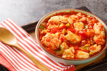 Ajoarriero is a traditional Spanish dish consists of shredded salt cod that's combined with tomatoes, garlic, onions, red and green peppers and potatoes closeup on the bowl on the table. Horizontal